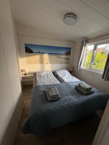 a bedroom with a bed with two towels on it at Camping Zeezicht - Chalet 16 in Westerland