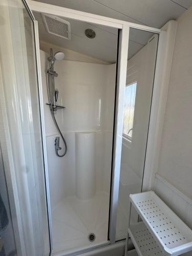 a shower with a glass door in a bathroom at Camping Zeezicht - Chalet 16 in Westerland