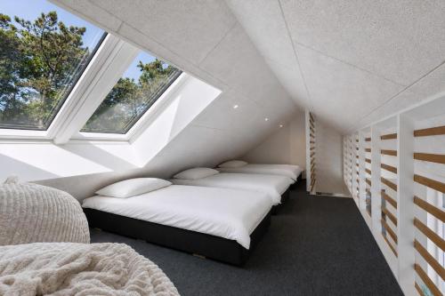 a attic bedroom with two beds and two windows at Feriehus 1116 in Ringkøbing