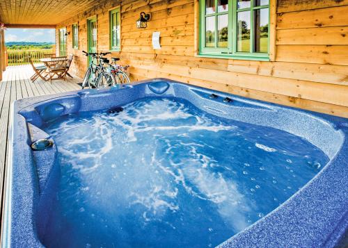 a jacuzzi tub in front of a wooden house at Oak Farm Lodges in Roydon
