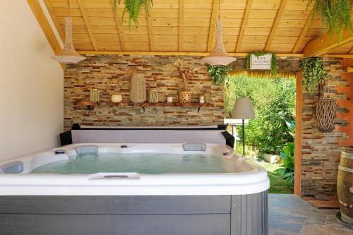 a hot tub in a room with a brick wall at Villa Lailléa avec piscine jacuzzi in Laillé