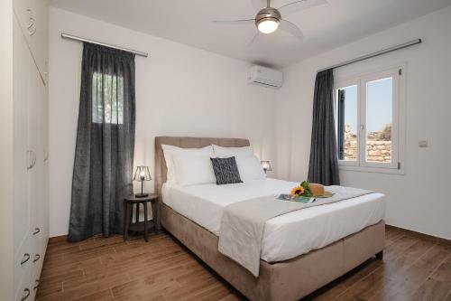 a bedroom with a large white bed and a window at Passa Corda Villa in Agios Prokopios