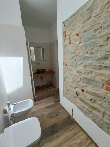 a bathroom with a stone wall next to a toilet at B&B La Piccola Lepre in Acqui Terme
