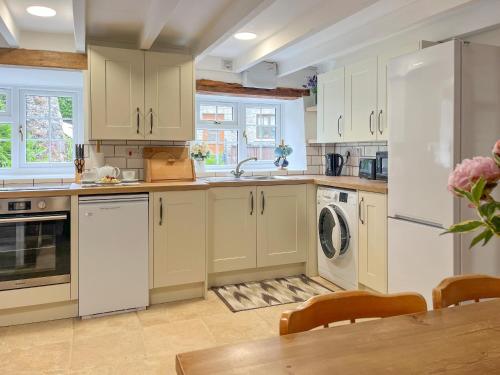 a kitchen with white cabinets and a sink and a table at Henwood Barn - Uk52138 in Liskeard