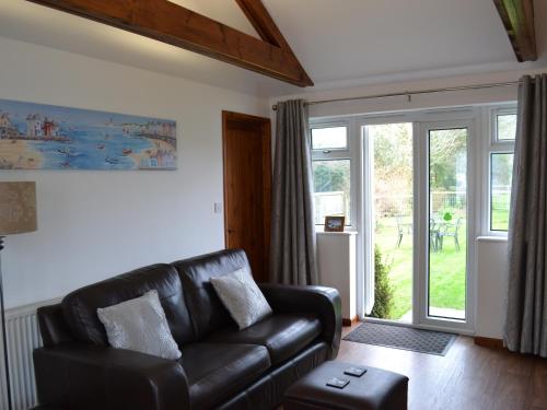 a living room with a leather couch and a sliding glass door at Summer Breeze in St Austell