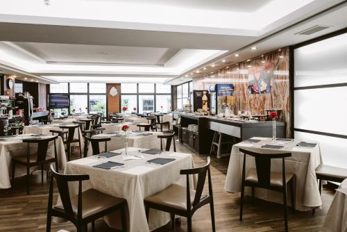 a restaurant with white tables and chairs and a bar at Hotel ILUNION Abando Bilbao in Bilbao