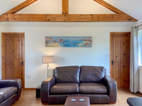 a living room with a leather couch and a table at Summer Breeze in St Austell