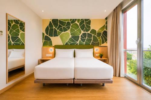 a bedroom with a white bed and a large window at Spirit Hotel Fonte Real in Monte Real