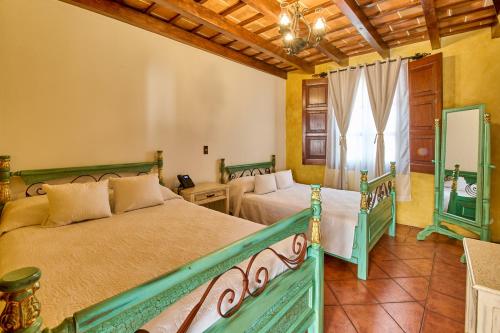 a bedroom with two beds and a window at Hotel El Descanso Cultural in Antigua Guatemala