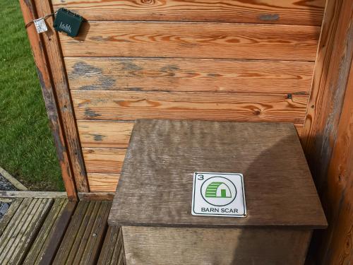 a bench with a sign on it next to a wooden wall at Barn Scar-Uk1394 in Corney
