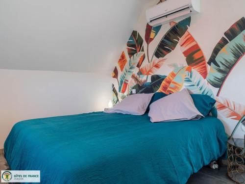 a bedroom with a blue bed with a tropical headboard at Ma Cabane in Mouret