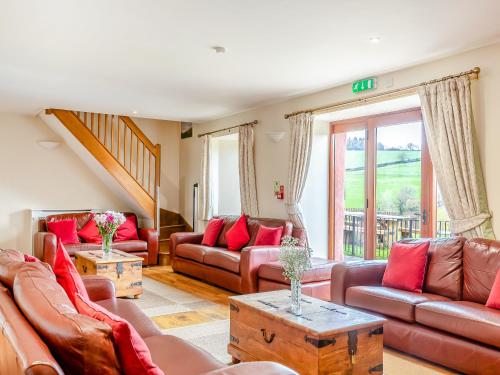 a living room with brown leather couches and red pillows at The Cider Barn - Hggl in Luton