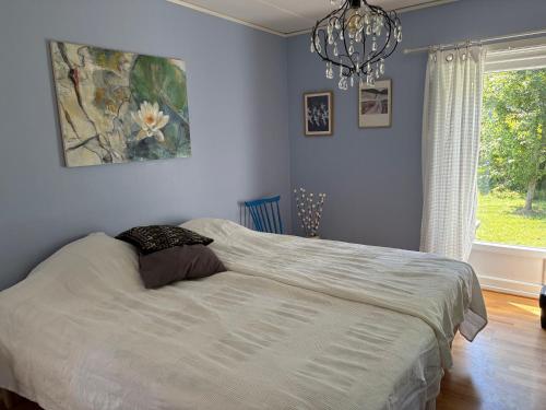 a bedroom with a bed with a chandelier and a window at Höga kusten Berghamn in Noraström