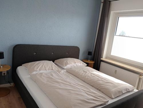 an unmade bed in a bedroom with a window at Haus Schildt, FeWo 3 in Duhnen