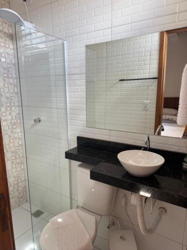 a bathroom with a toilet and a sink and a shower at Hotel Ipe in Barreirinhas