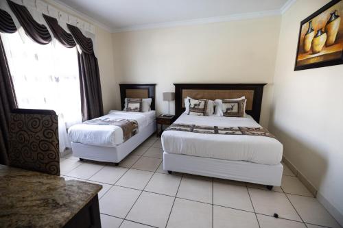 a bedroom with two beds and a window at Ecotel Southgate in Southgate