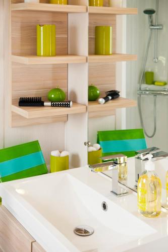 La salle de bains est pourvue d'un lavabo et de 2 chaises vertes. dans l'établissement Camping Paradis Le Pearl, à Argelès-sur-Mer