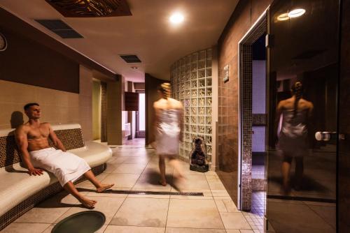 Ein Mann sitzt in einem Badezimmer mit Schaufensterpuppen auf einem Sofa. in der Unterkunft Hotel Eroplán in Rožnov pod Radhoštěm