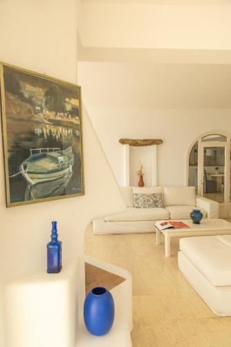 a living room with white furniture and a painting of a boat at Eagles Nest Mykonos Suites & Apartments - Shared Pool & Jacuzzis in Mikonos