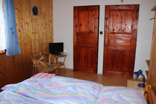 a bedroom with a bed and two wooden doors at Penzion Pod Rozhlednou in Janov