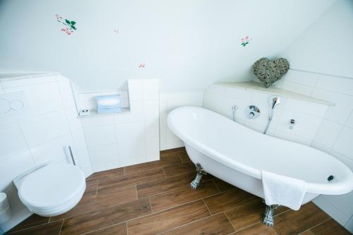 a white bathroom with a tub and a toilet at Seehotel Burg Spreewald in Byhleguhrer Kaupen
