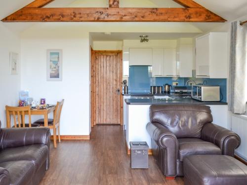 a living room with two leather couches and a kitchen at Sunset in St Austell