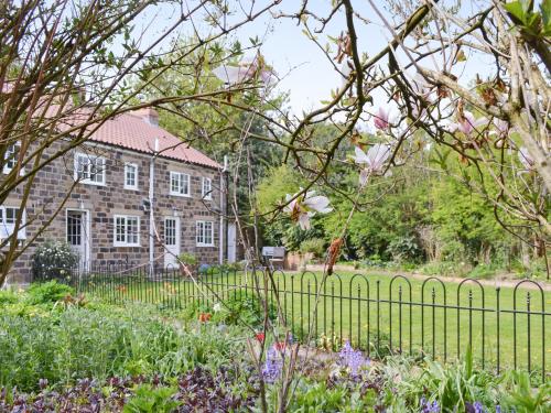 a fence in front of a house with flowers at Keldholme Cottage 1 - Uk10992 in Kirkbymoorside