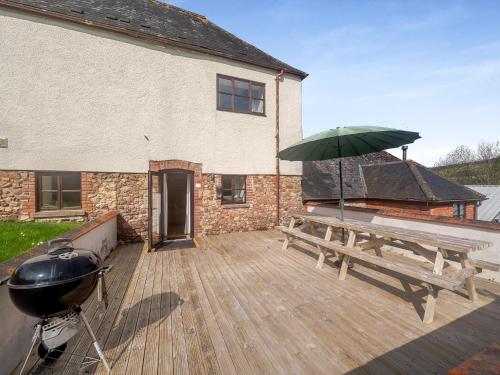 a grill and a picnic table with an umbrella on a deck at Madeleine - Hja in Luton