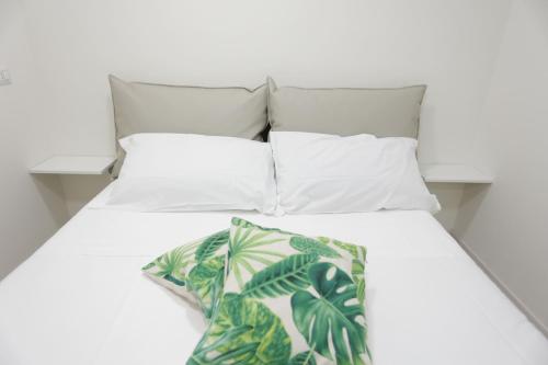 ein weißes Bett mit weißen Kissen und einer grünen Decke in der Unterkunft Path House by Wonderful Italy in Riposto