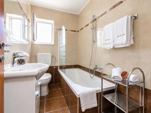 a bathroom with a tub and a toilet and a sink at Mare & Mons Seafront Apartments in Malinska