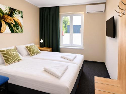a hotel room with two beds and a window at Samoobsługowy Hotel Astoria Fly Modlin Airport in Pomiechówek