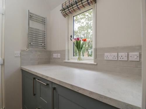 a kitchen with a vase of flowers in a window at Foxglove in Bicester