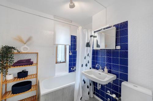 a bathroom with blue tiles and a sink and a tub at Schanzenblick mit Sauna und Pool in Schönwald
