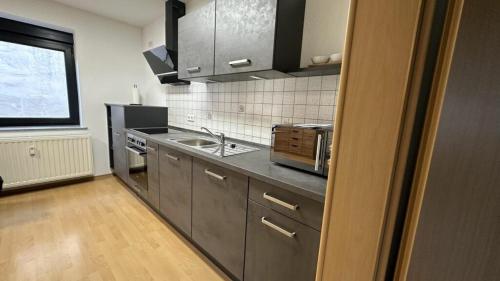 a kitchen with gray cabinets and a sink and a window at Ferienwohnung Bickenalb in Zweibrücken