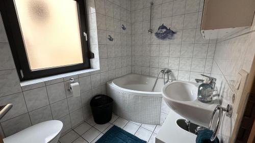 a bathroom with a sink and a bath tub at Ferienwohnung Bickenalb in Zweibrücken