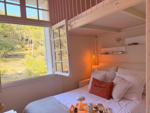 a bedroom with a bed and a large window at La Boîte Rose - Studio plage de l'Almanarre in Hyères