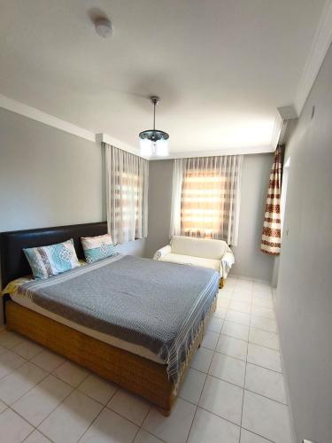 a bedroom with a bed and a chair in it at Sea View Villa w Garden 50m to Sarımsaklı Beach in Ayvalık