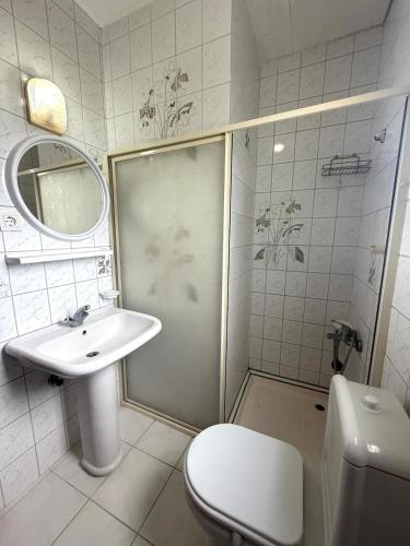 a white bathroom with a toilet and a sink at Sea View Villa w Garden 50m to Sarımsaklı Beach in Ayvalık
