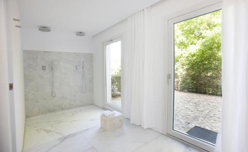 La salle de bains blanche est pourvue d'une douche et d'une grande fenêtre. dans l'établissement Quinta Do Miguel, à Aldeia do Meco
