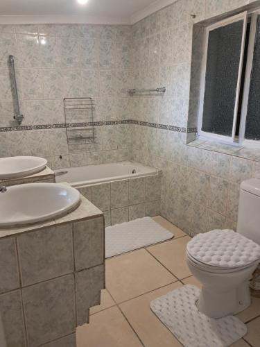 a bathroom with a toilet and a sink and a tub at Charles Guest House in Germiston