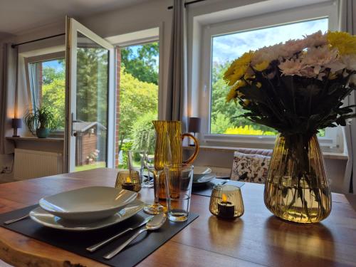 a dining room table with a vase of flowers on it at Vogelkoje - Urlaub an der Nordsee in Nordfriesland in Bredstedt