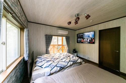 a bedroom with a bed and a window and a tv at コテージひだまり in Izunokuni