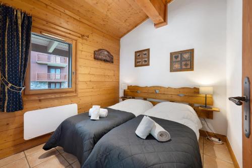 two beds in a room with wooden walls at Appartement Airelles B25 in Levassaix