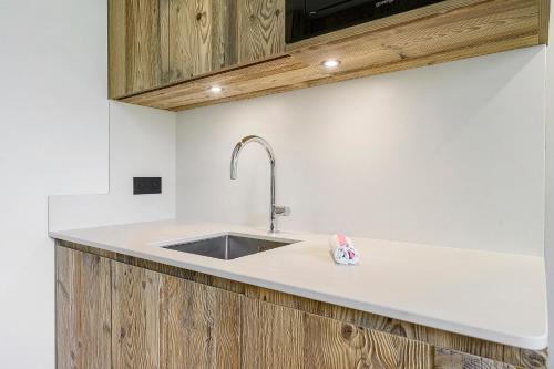 a kitchen with a sink and wooden cabinets at Appartement Le Panorama Des Pistes in Les Menuires