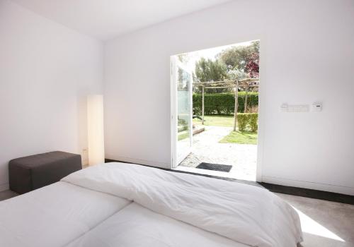 a bedroom with a white bed and a large window at Quinta Do Miguel in Aldeia do Meco