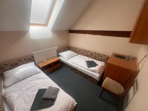 a bedroom with two beds and a desk and a window at Sudický Dvur in Boskovice