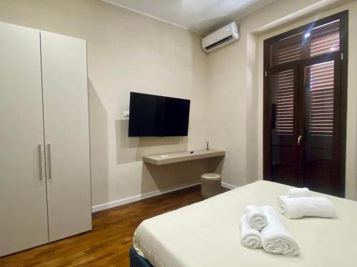 a bedroom with a bed and a flat screen tv at Helios Home in Reggio di Calabria