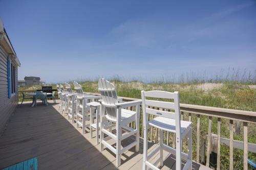 a row of white chairs sitting on a deck overlooking the ocean at 5010 - Once Upon A Tide in Kill Devil Hills