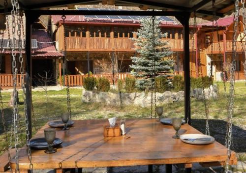 Ein Holztisch in einem Pavillon mit Tellern und Weingläsern in der Unterkunft Haleb Hotel Complex in Dilidschan