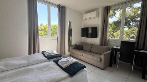 a bedroom with a bed and a couch and windows at Kimi Résidence in Cannes